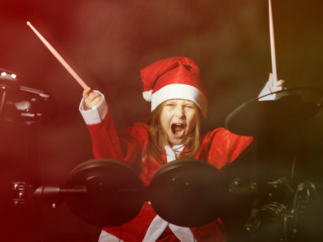 Little drummer disguised as Santa Claus playing the electronic drum kit